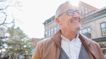 Happy Caucasian senior man smiles cheerfully while outdoors.